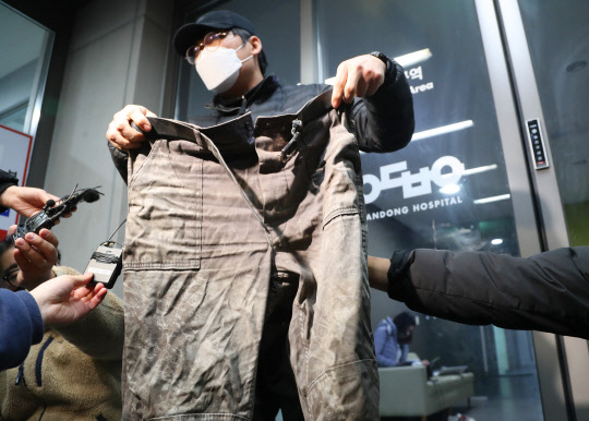 5일 경북 안동병원 응급실 앞에서 봉화군 아연광산 매몰사고로 고립됐다가 구조된 작업반장 박모(62)씨의 아들 박근형(42)씨가 고립 당시 박씨가 입고 있던 작업복을 취재진에게 보여주고 있다. [봉화=연합뉴스]